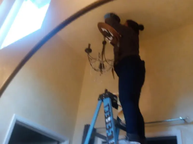 Electrician installing a chandelier in a Miami Shores residence